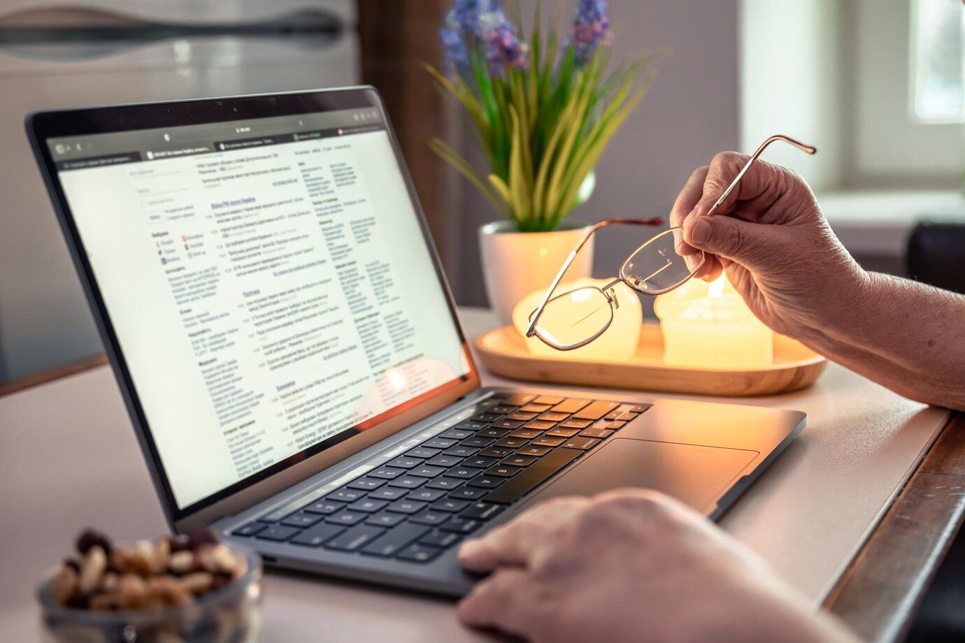 Una persona escribe en una computadora portátil con gafas.