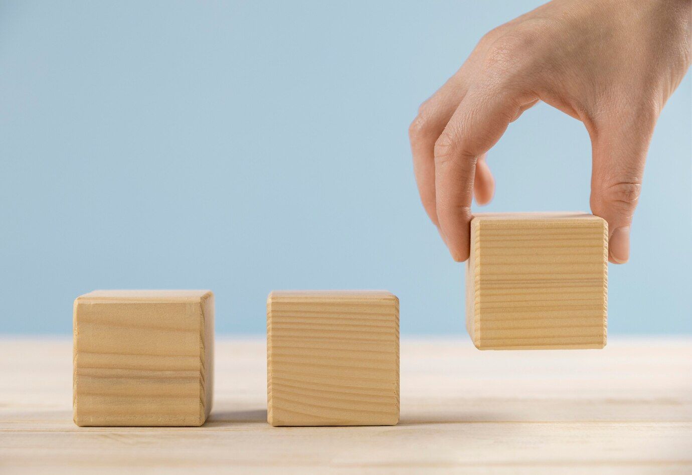 Una persona está apilando bloques de madera uno encima del otro sobre una mesa.