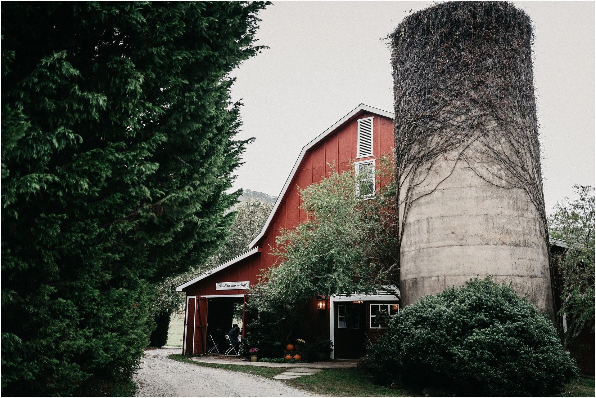 A red barn with a silo in front of it