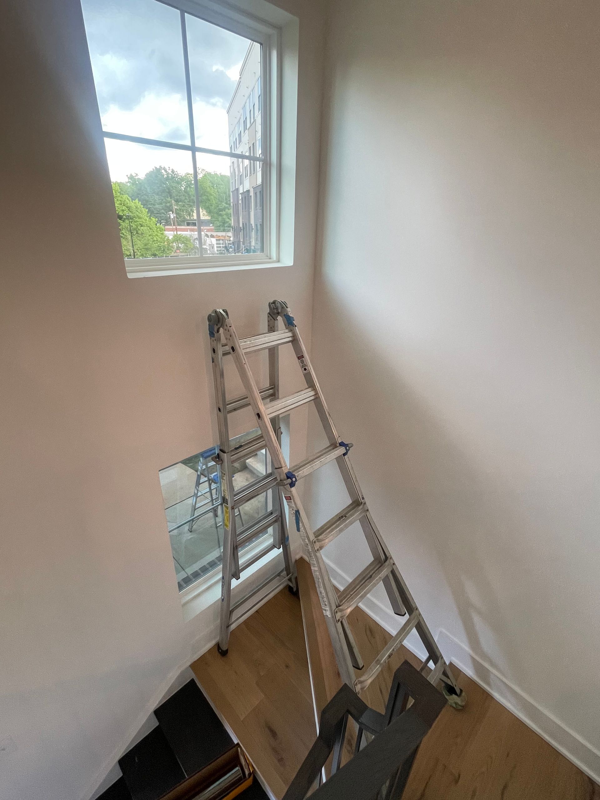 A ladder is sitting in a room next to a window.