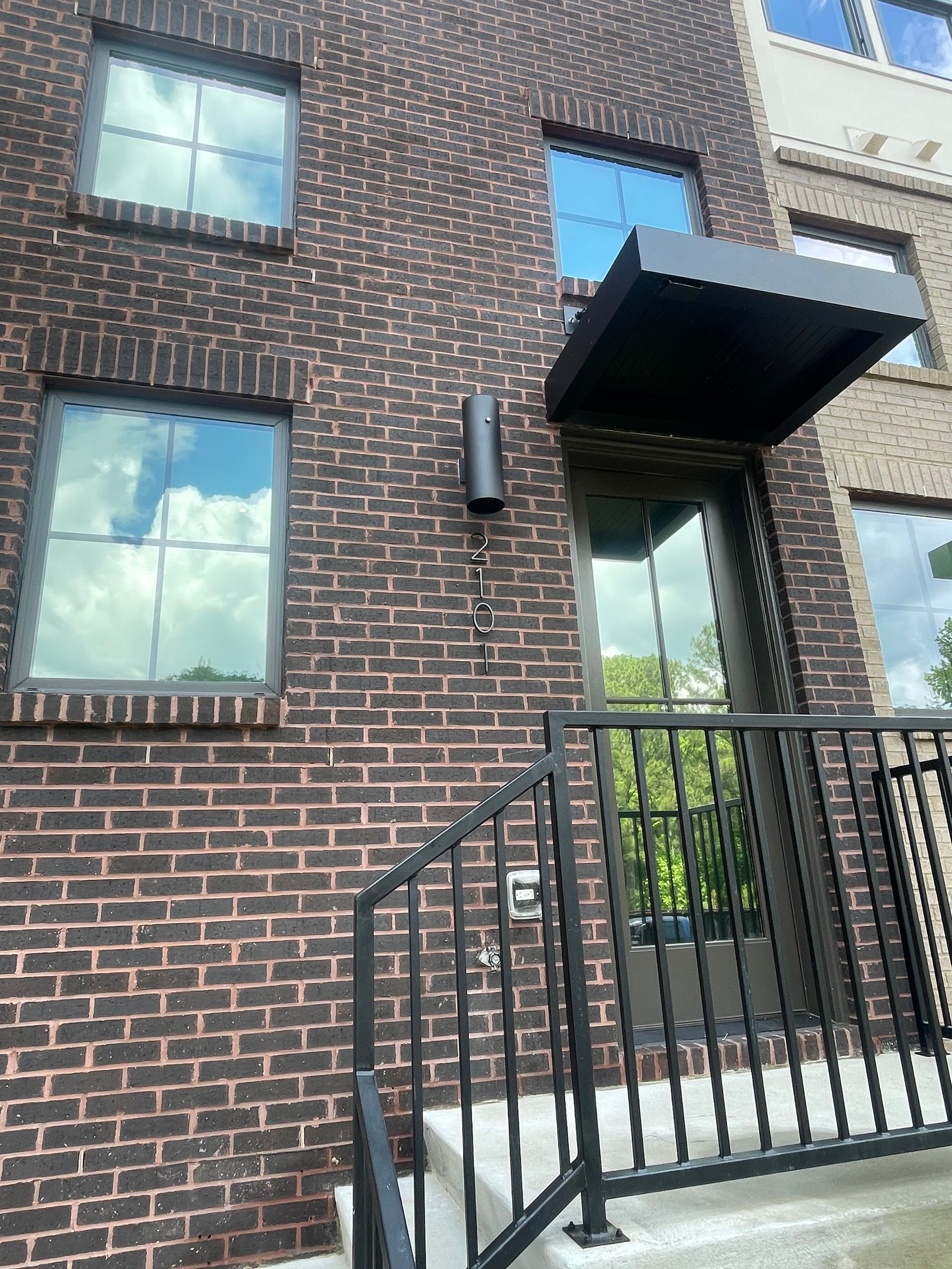 A brick building with a canopy over the door and stairs leading up to it.