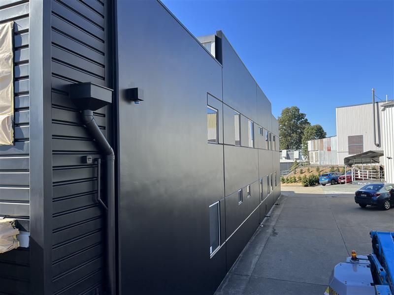 A large black building with a blue truck parked in front of it.