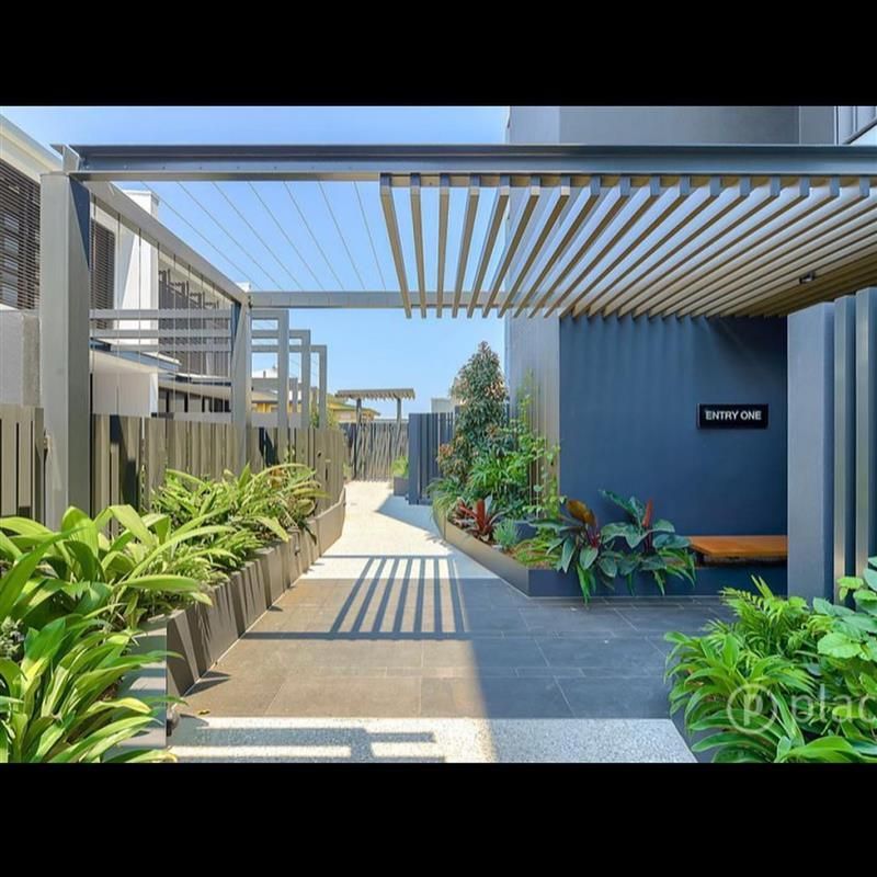 A walkway leading to a building with a pergola over it