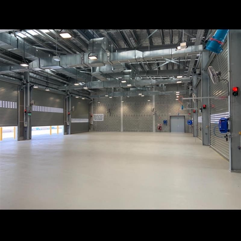 A large empty warehouse with a lot of doors and ventilation ducts.