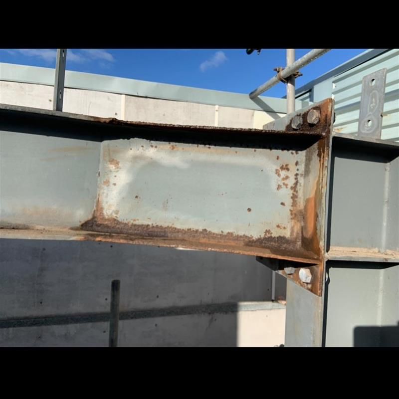 A close up of a rusty metal structure with a blue sky in the background