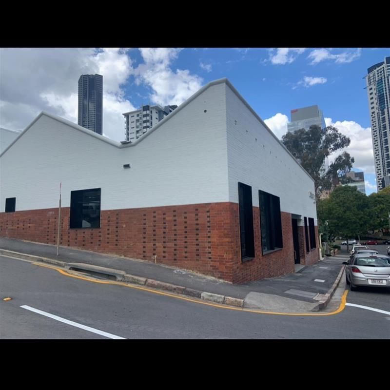 A white building with a brick facade is on the corner of a street