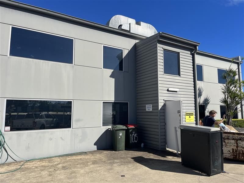 A large building with a lot of windows and a dumpster in front of it.