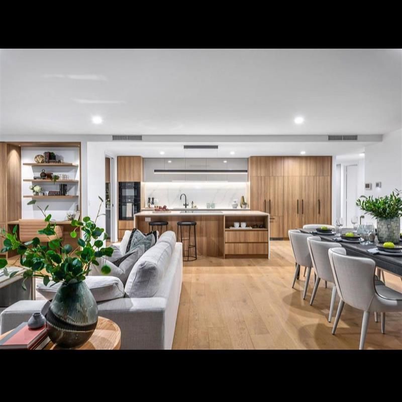 A living room with a couch , chairs , a table and a kitchen.