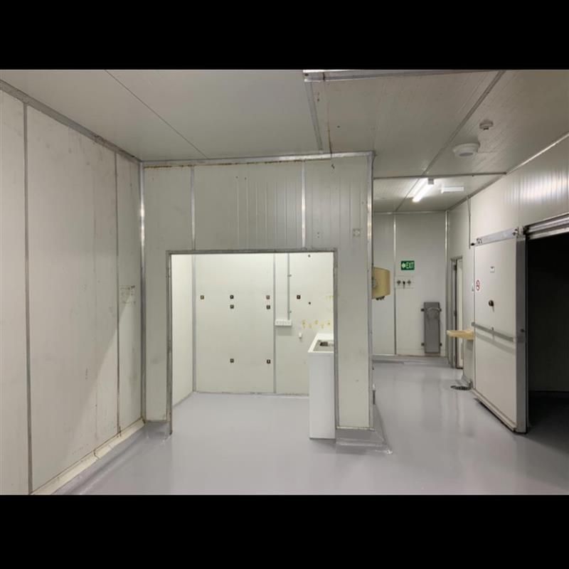 An empty room with white walls and a green exit sign