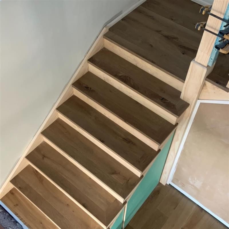 A set of wooden stairs with a green railing