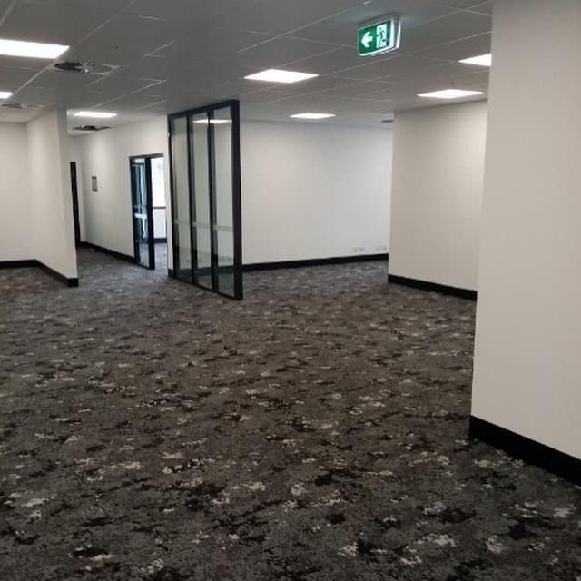A large empty room with a black carpet and white walls.