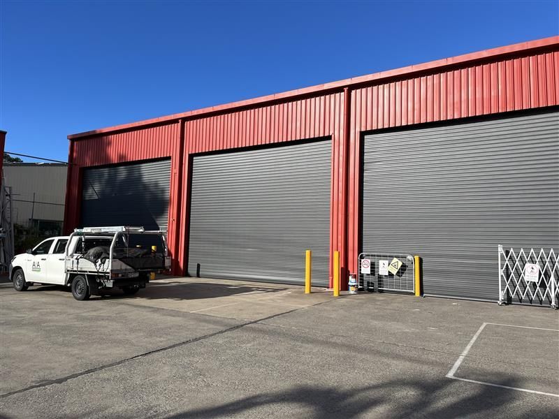 A white truck is parked in front of a red building.