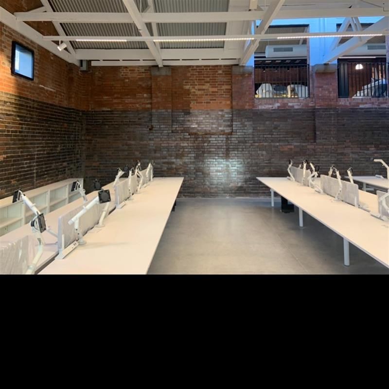 A room with a brick wall and white tables and chairs