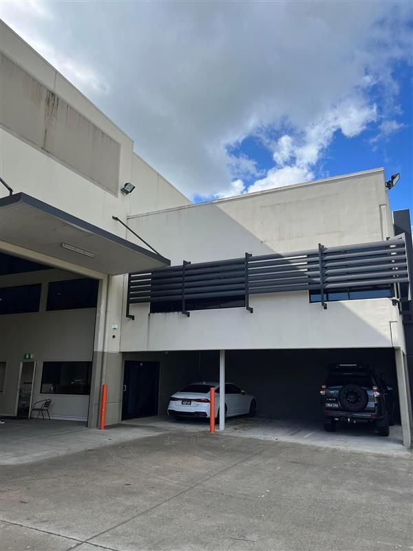 A white building with a car parked underneath it.