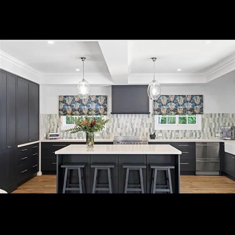 A kitchen with black cabinets and stools and a large island in the middle.