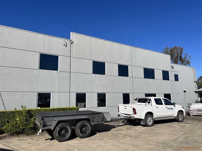 A white truck is parked in front of a building with a trailer attached to it.