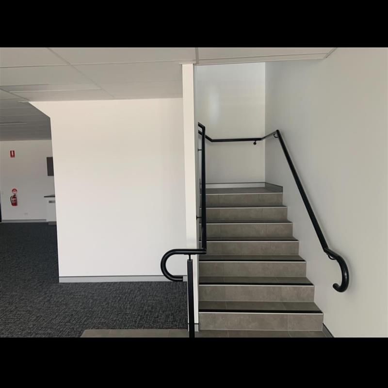 A set of stairs with a black railing in an empty room