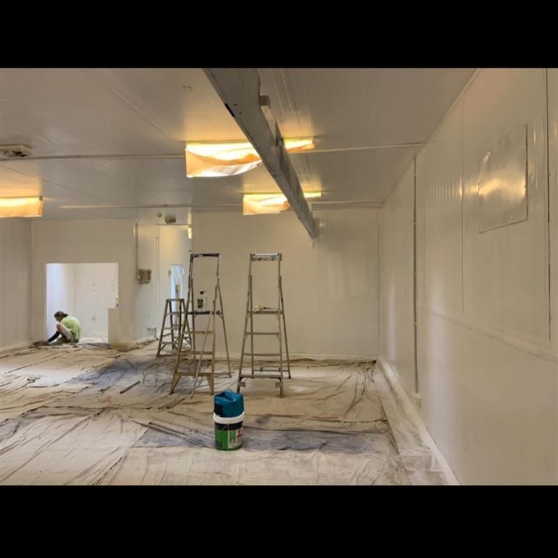 A man is painting a wall in an empty room