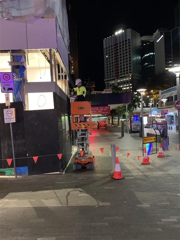 A construction worker is working on a building at night.