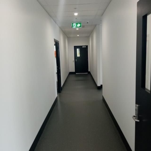 A long hallway with a green exit sign on the ceiling