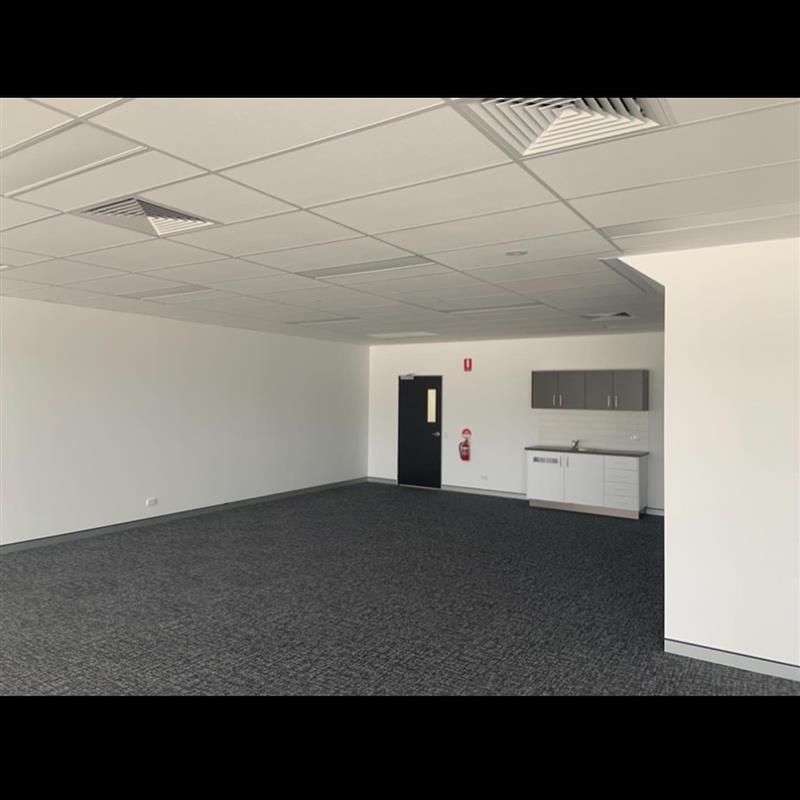 A large empty room with a carpeted floor and white walls.
