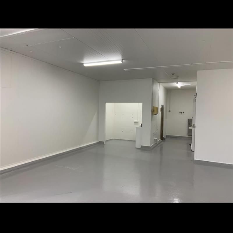 A large empty room with white walls and a gray floor.