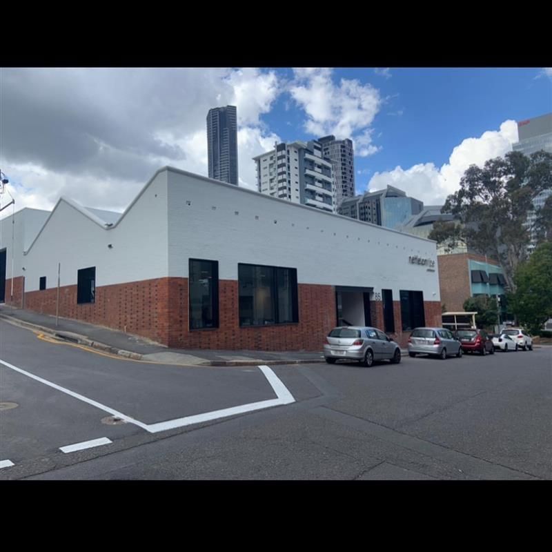 A row of cars are parked in front of a white building