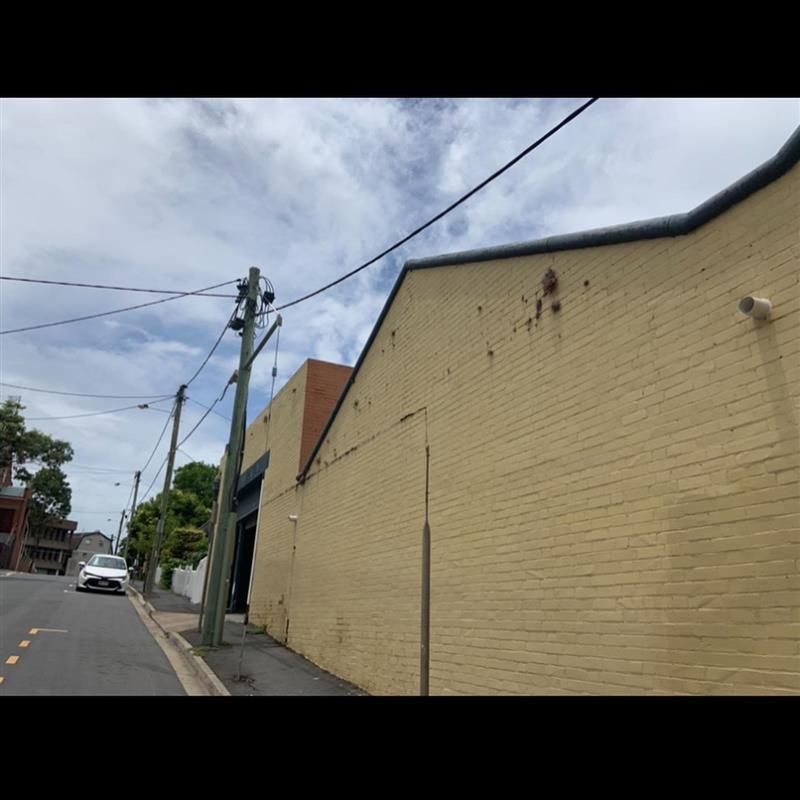 A yellow brick building with a white car parked in front of it