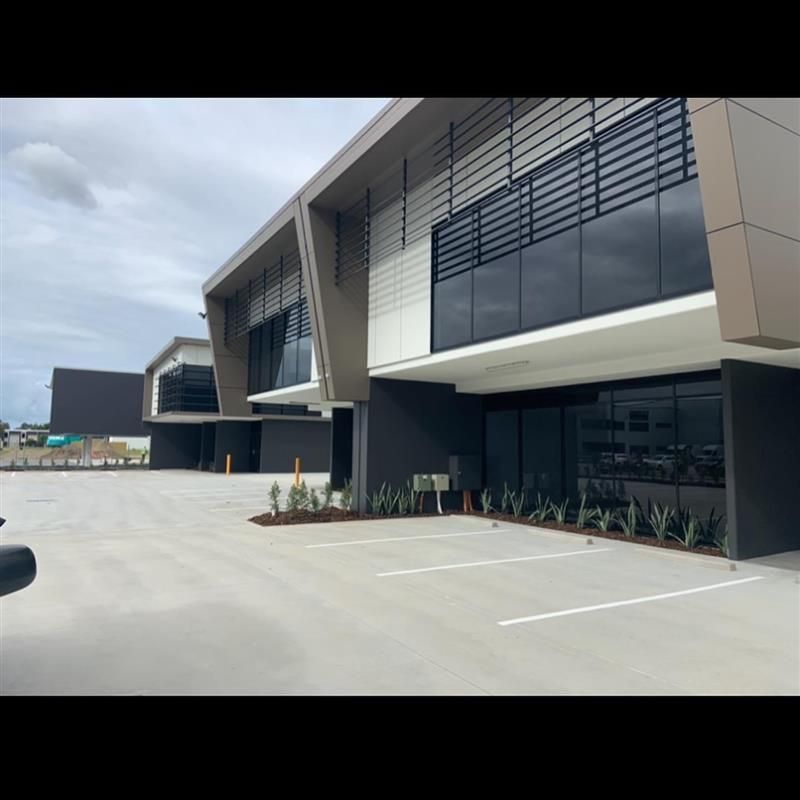 A large building with a lot of windows and a parking lot in front of it