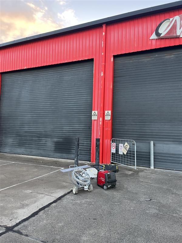 A red building with black shutters and a trolley in front of it.