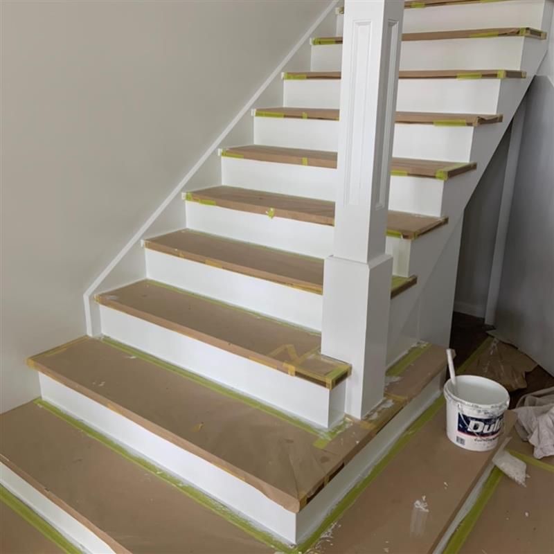 A staircase is being painted with a bucket of dulux paint