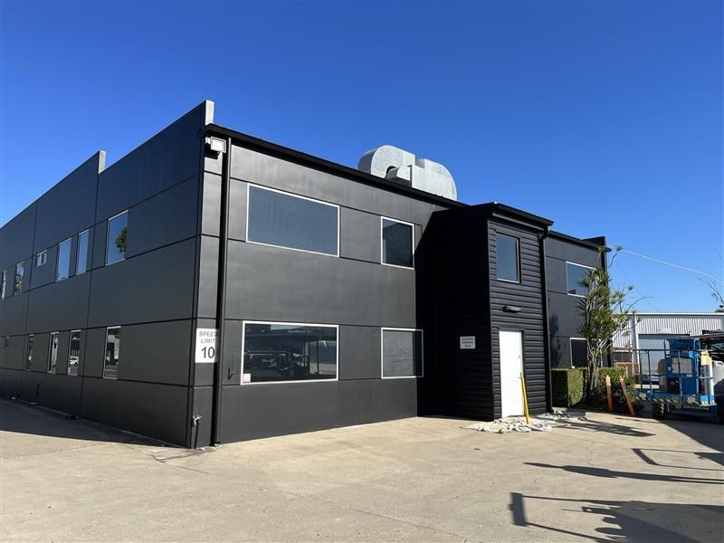 A large black building with a lot of windows and a blue truck parked in front of it.
