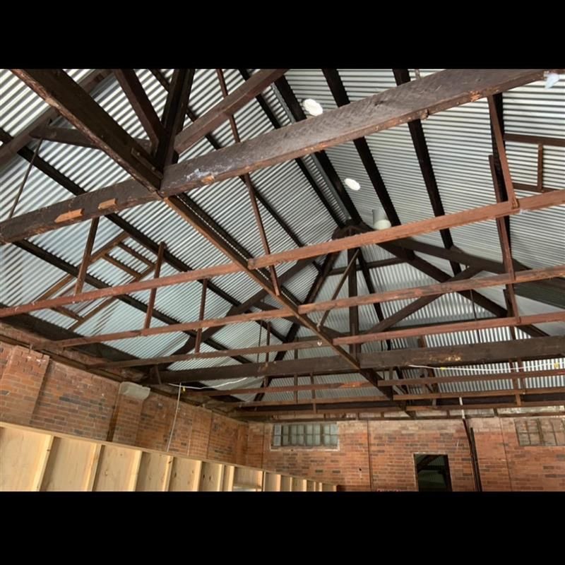 The ceiling of a building with wooden beams and a metal roof.