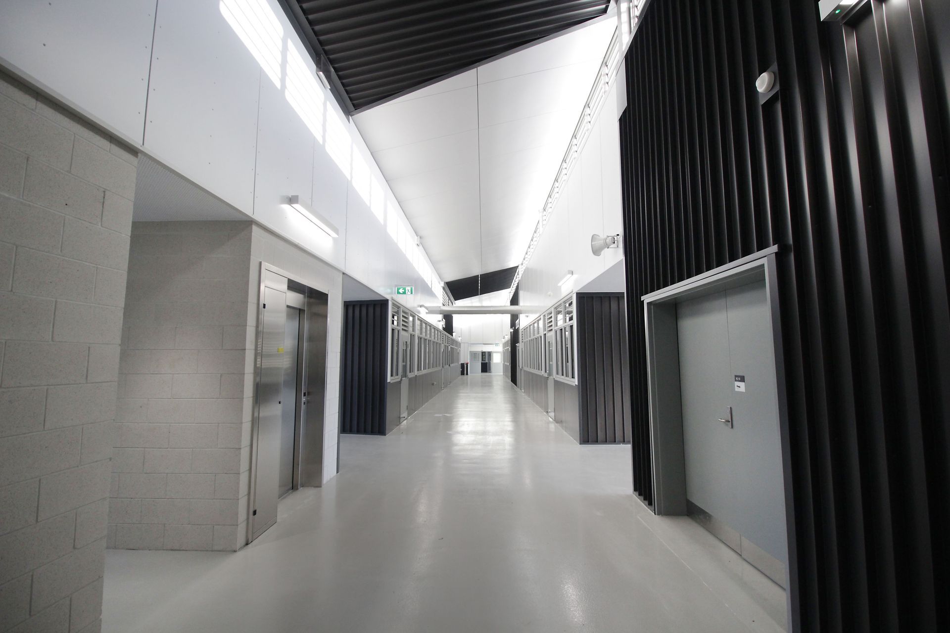 A long hallway with elevators and doors in a building.
