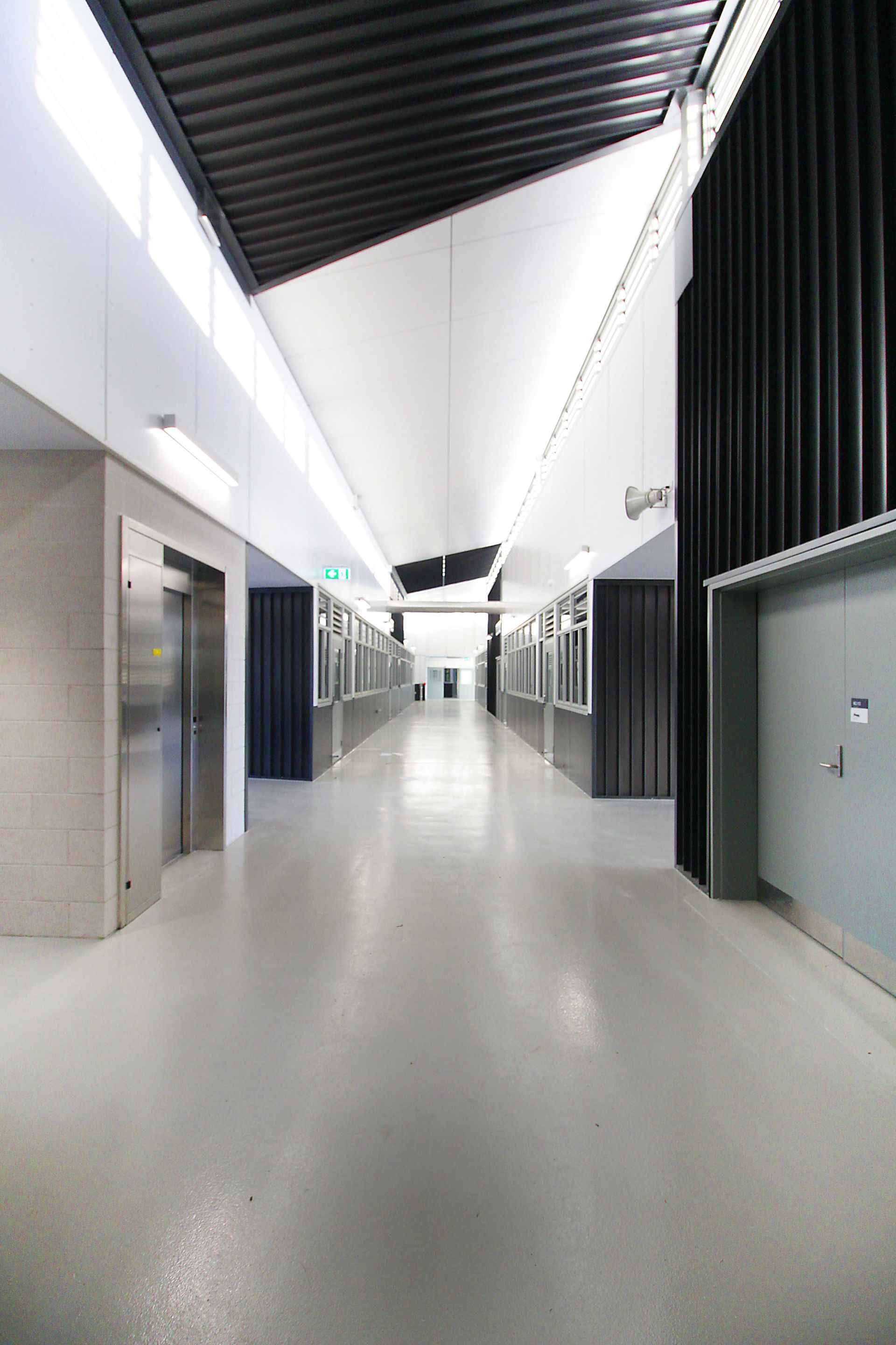 A long hallway in a building with elevators and doors.