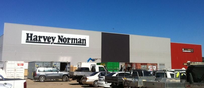 A harvey norman store with cars parked in front of it