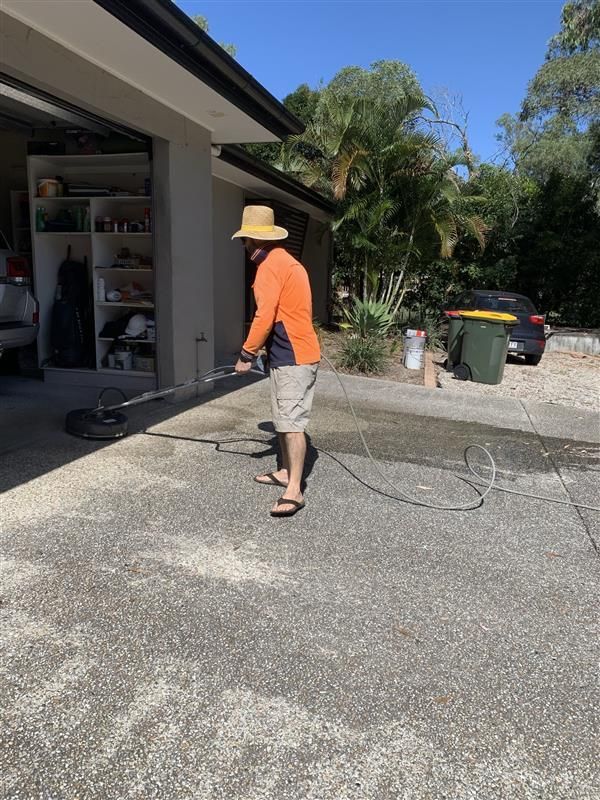 A man is cleaning a driveway with a pressure washer.