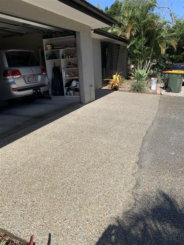 A car is parked in a garage next to a trash can.
