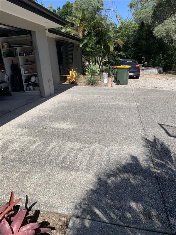 A car is parked in a driveway next to a garage.