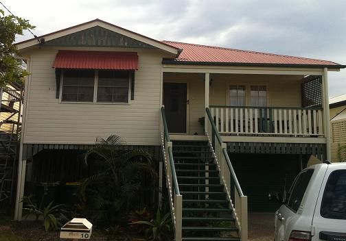 A white house with stairs and a red roof