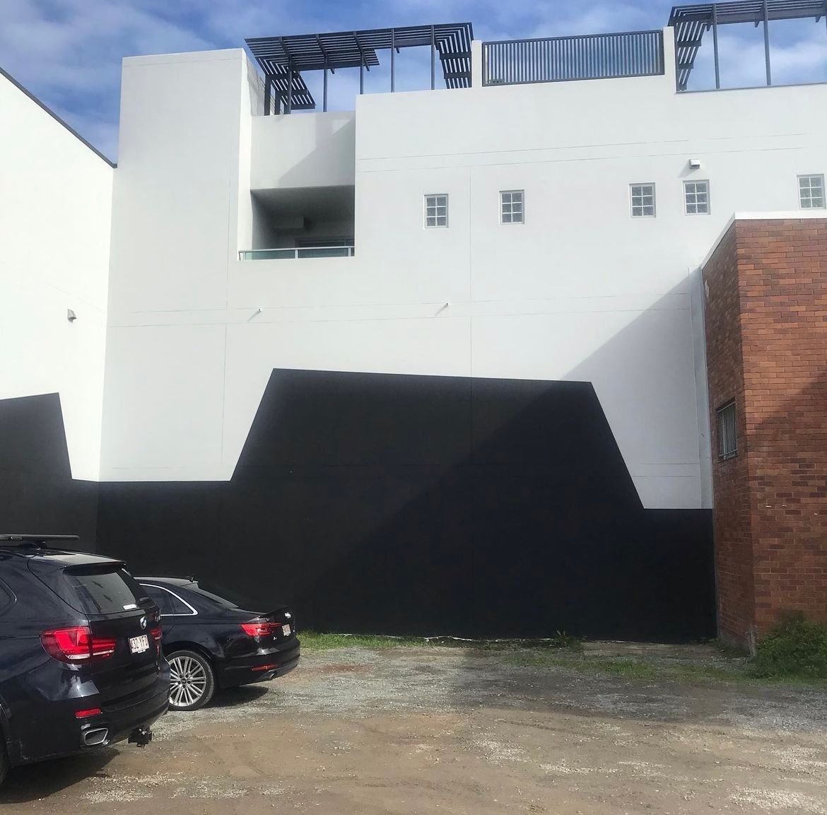 A black and white building with cars parked in front of it