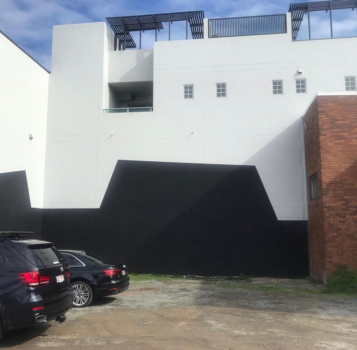 A row of cars are parked in front of a large white building