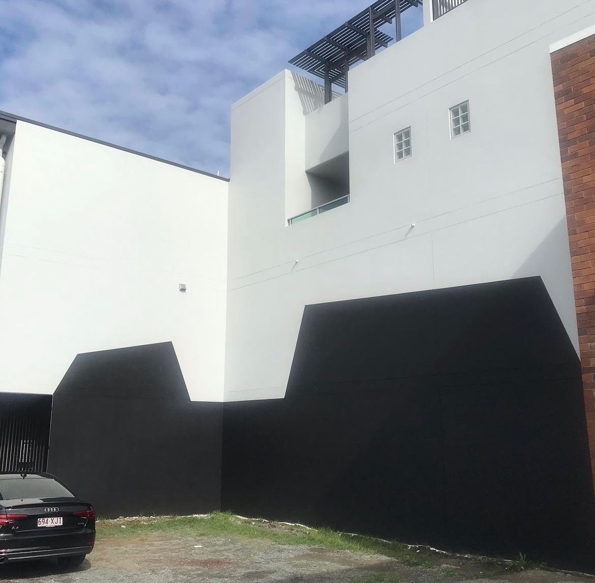 A black car is parked in front of a white building