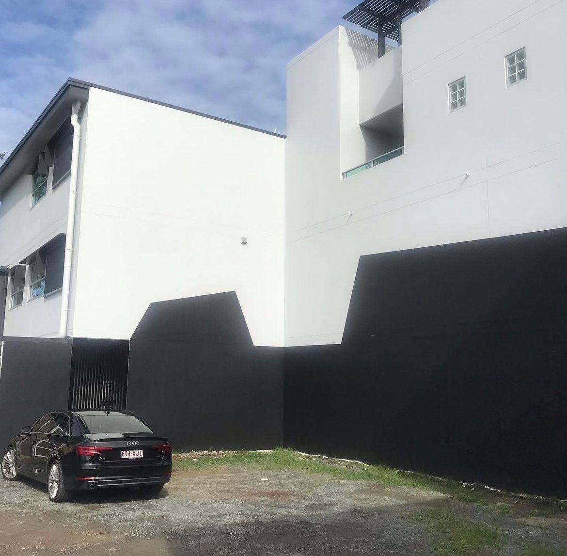 A black car is parked in front of a white building
