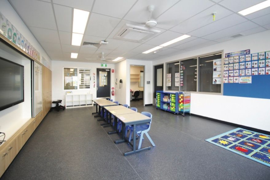 A large classroom with tables and chairs in it