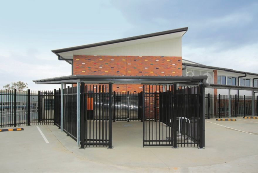 A brick building with a black fence around it