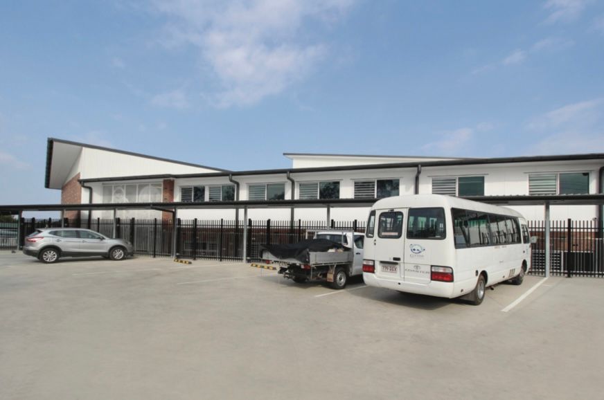 A white van is parked in a parking lot in front of a building.