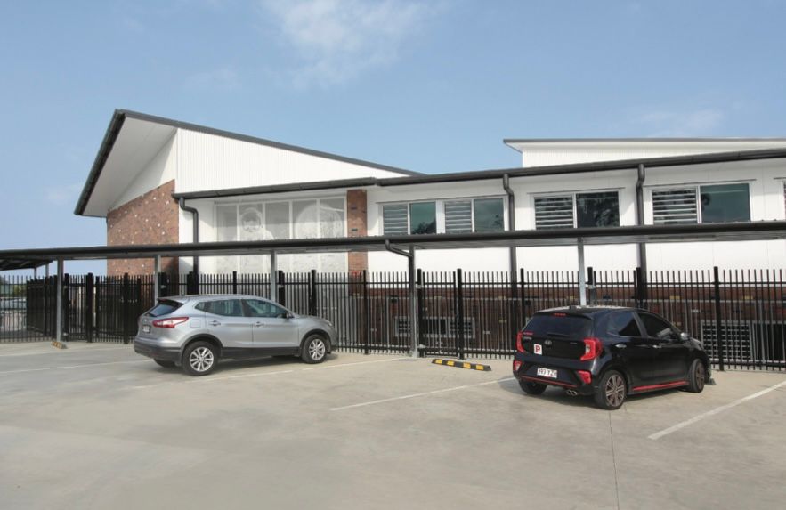 Two cars are parked in a parking lot in front of a building.