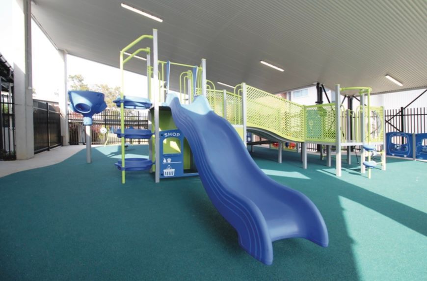 A blue slide is in the middle of a playground.