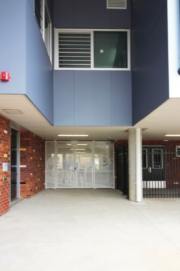 A blue building with a white door and a red fire alarm